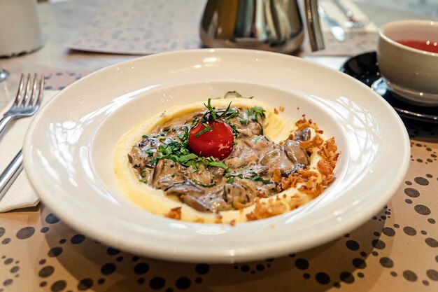 Traditional beef stroganoff in a ceramic bowl with mashed potato on a wooden table, selective focus