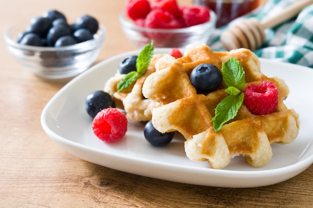 Traditional belgian waffles with blueberries and raspberries on wooden table