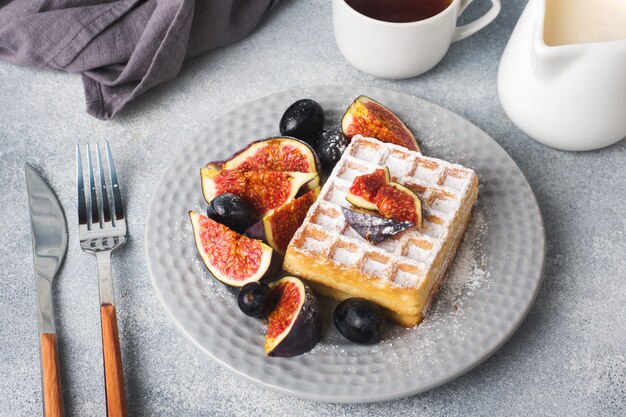 Traditional Belgian waffles with powdered sugar grapes and figs. 