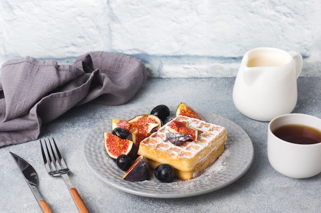 Traditional Belgian waffles with powdered sugar grapes and figs. 