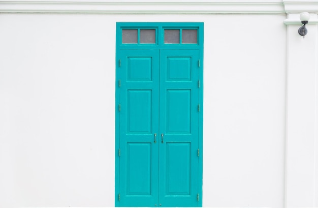 Traditional blue door wooden of an old on white wallin Thailand