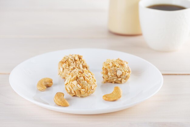 Traditional Brazilian candy truffles brigadeiro with cashew nuts on a white plate on the table