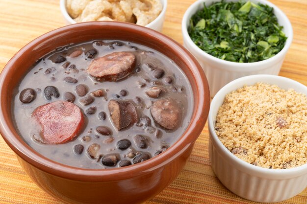 Traditional brazilian feijoada with orange, kale and manioc flour.