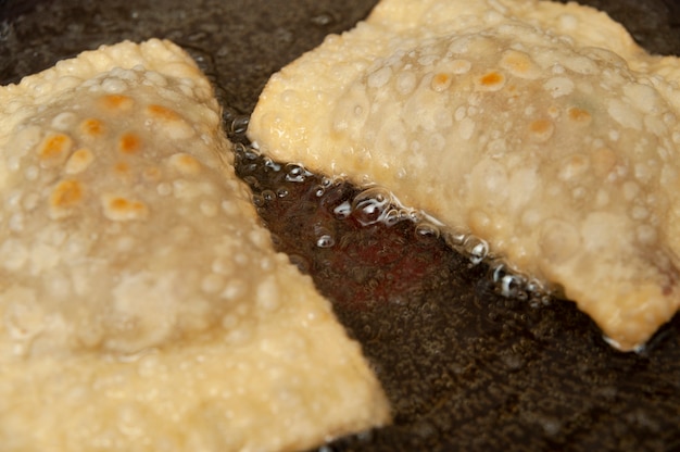 Traditional Brazilian food called Pastel in Brazilian Portuguese being fried in cooking oil