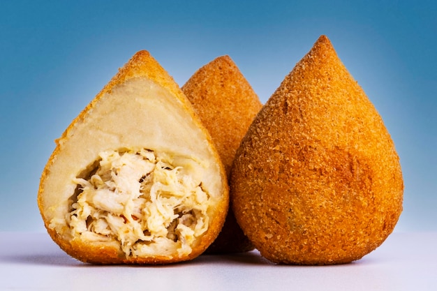 Traditional Brazilian snacks on a blue gradient background - coxinha.