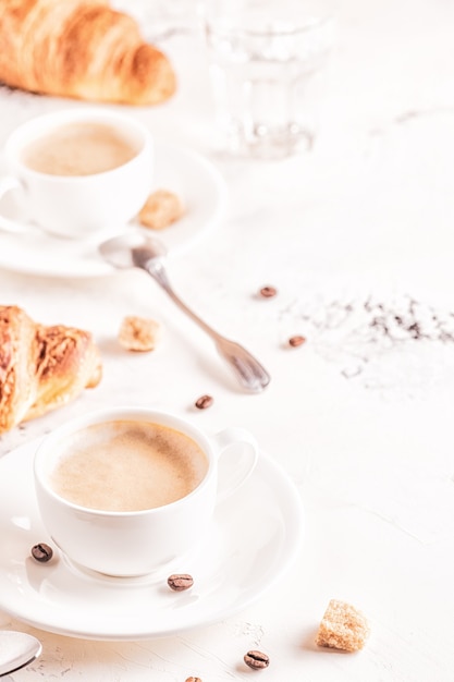 Traditional breakfast with fresh croissants on white surface, vertical.