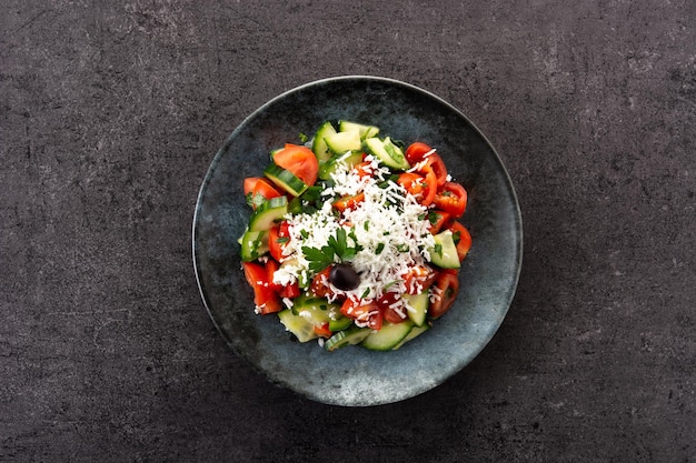 Traditional Bulgarian shopska salad with tomatocucumber and bulgarian sirene cheese on black background