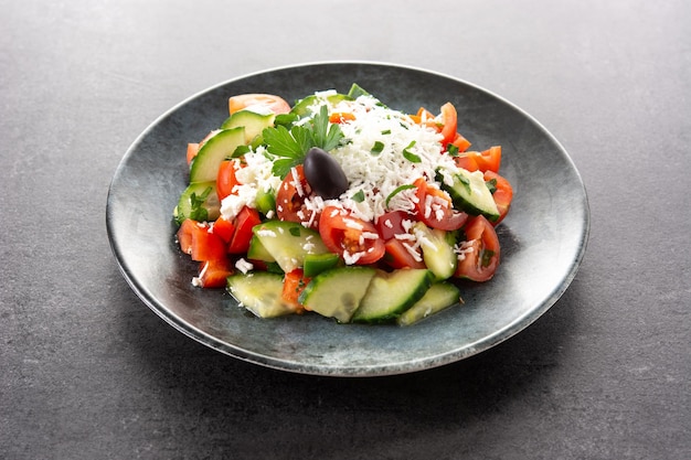 Photo traditional bulgarian shopska salad with tomatocucumber and bulgarian sirene cheese on black slate background