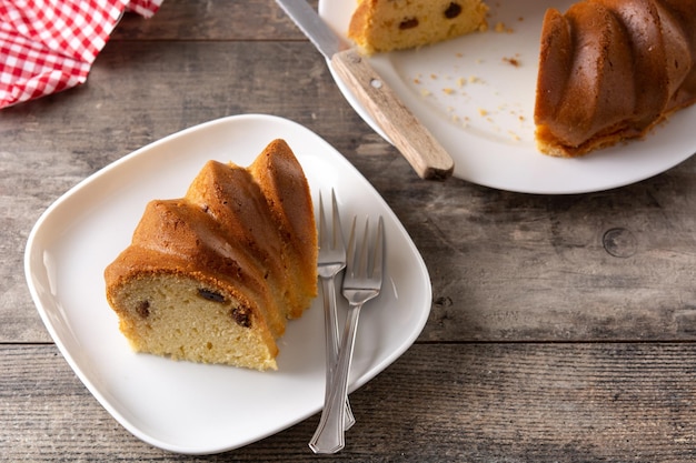 Traditional bundt cake piece with raisins on wooden table