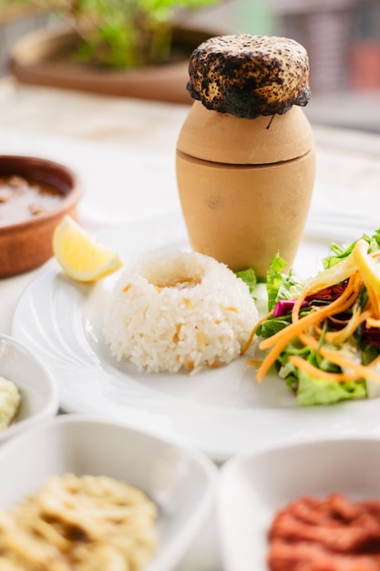 도자기로 만든 전통 카파도키아 터키 음식, 괴레메 시의 케밥이 샐러드와 쌀과 함께 테이블에 제공됩니다.