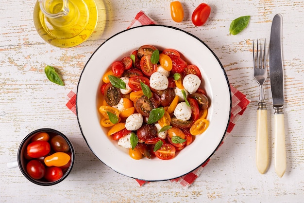 traditional caprese salad made of sliced fresh tomatoes, mozzarella cheese and basil, top view