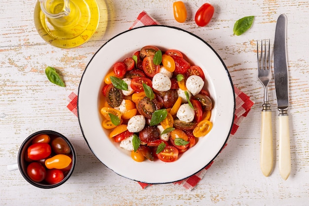 Traditional Caprese salad made of sliced fresh tomatoes, mozzarella cheese and basil, top view