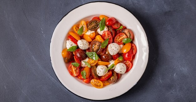 Traditional Caprese salad made of sliced fresh tomatoes, mozzarella cheese and basil, top view