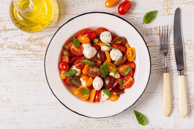 Traditional Caprese salad made of sliced fresh tomatoes, mozzarella cheese and basil, top view