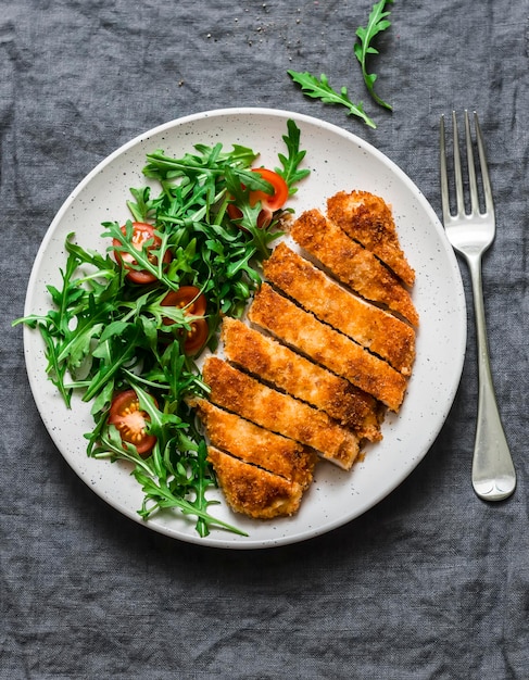 Traditional chicken schnitzel with arugula cherry tomatoes salad