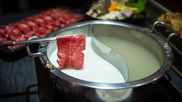 Traditional chinese hot pot style with a brass pot. Dining table, raw and fresh ingredients. Delicious beef in famous copper jars hotpot at China. Food concept.