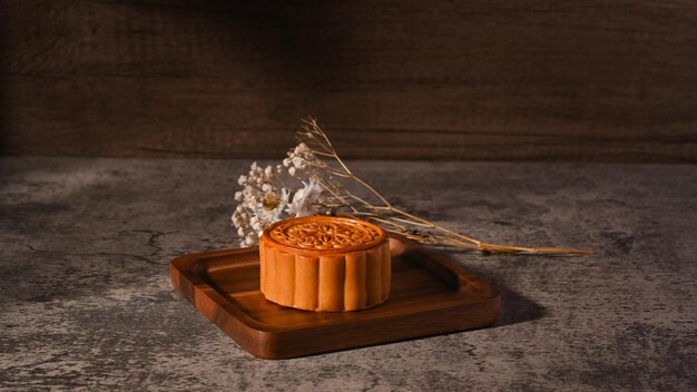 Traditional Chinese mooncakes with tea and decorating with dried flower on rustic stone background