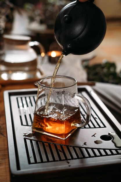 Traditional chinese tea ceremony gun fu cha and pouring oolong\
from a teapot with vapor on a dark background