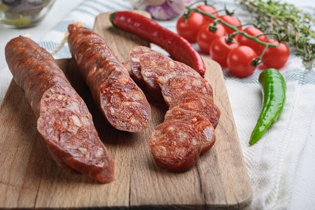 Traditional chorizo cuts with spices and ingredients on white textured surface.