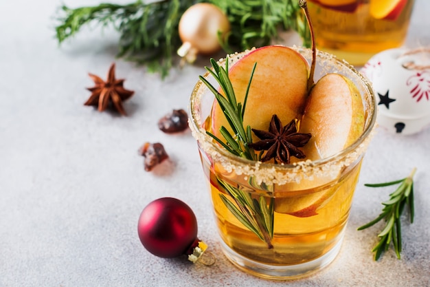 Traditional Christmas apple punch with cinnamon, anise and sprigs of rosemary on light table