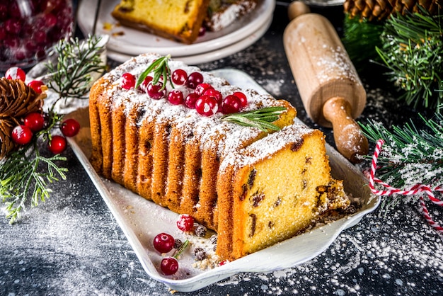 Traditional christmas baking, Festive Xmas fruitcake with dryed fruits, liquer, and cranberry decor. Homemade fruitcake on Chritmas decorated background