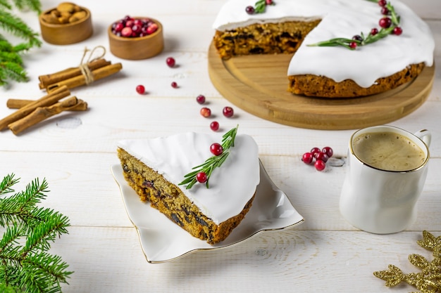 Traditional Christmas cake with fruits, nuts and white glaze with decorations and a cup of coffee