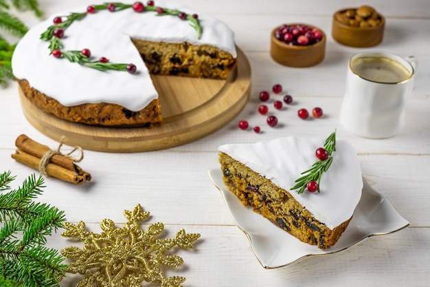 Traditional Christmas cake with fruits, nuts and white glaze with decorations and a cup of coffee