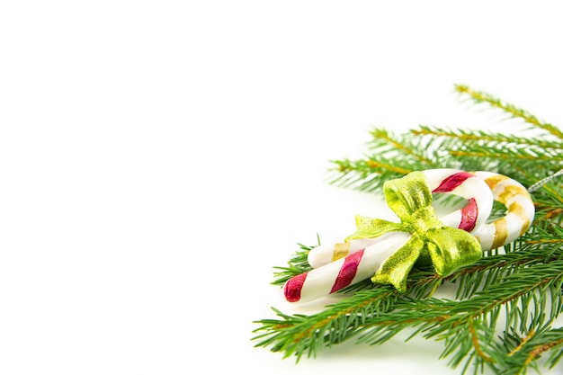 Foto tradizionale bastoncino di zucchero di natale su un ramo di abete vicino isolato su uno sfondo bianco