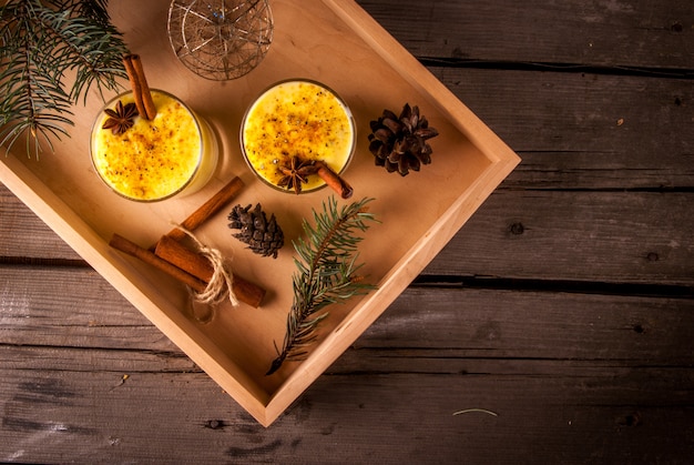 Traditional Christmas drink eggnog on a wooden background