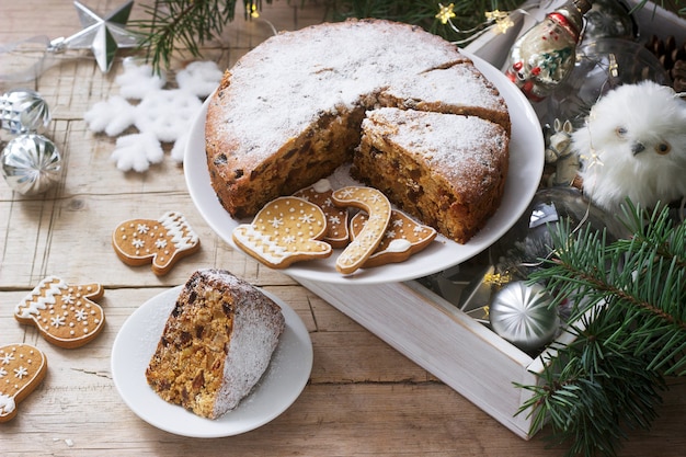 Traditional Christmas fruitcake on the of a box with Christmas toys and fir branches.