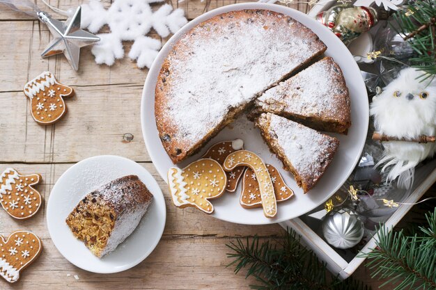 Traditional Christmas fruitcake on  a box with Christmas toys and fir branches.