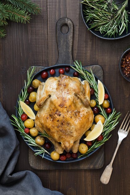 Photo traditional christmas roasted chicken with potatoes and rosemary on wooden table top view