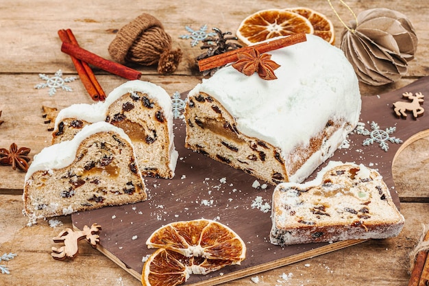 Traditional Christmas stollen German cake European pastry fragrant home baked bread with spices and dried fruit Xmas tree branches and decorations wooden background close up