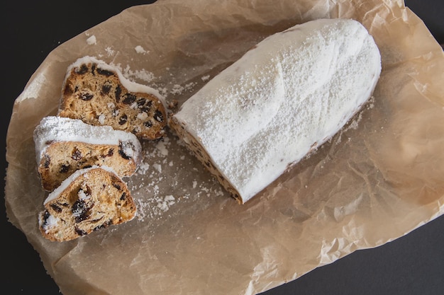 Traditional Christmas stollen made of dried fruits and nuts sprinkled with powdered sugar