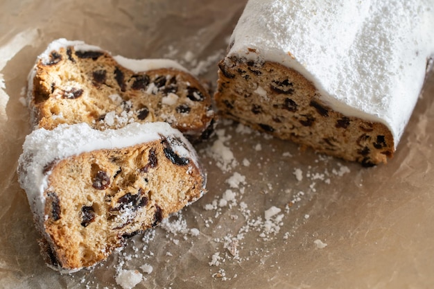 Traditional Christmas stollen made of dried fruits and nuts sprinkled with powdered sugar