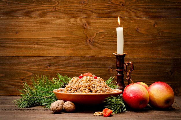 Traditional Christmas treat of the Slavs on Christmas eve kutia. Fir branch, apples, candle on wooden background