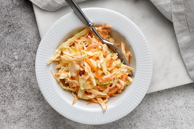 Traditional coleslaw salad with fresh sliced carrots and cabbage in white bowl copy space Cole slaw