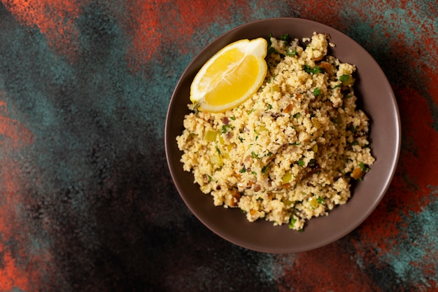 Traditional couscous with vegetables and herbs in a bowl. Levantine vegetarian salad. Lebanese, arabic cuisine. Top view. Copy space