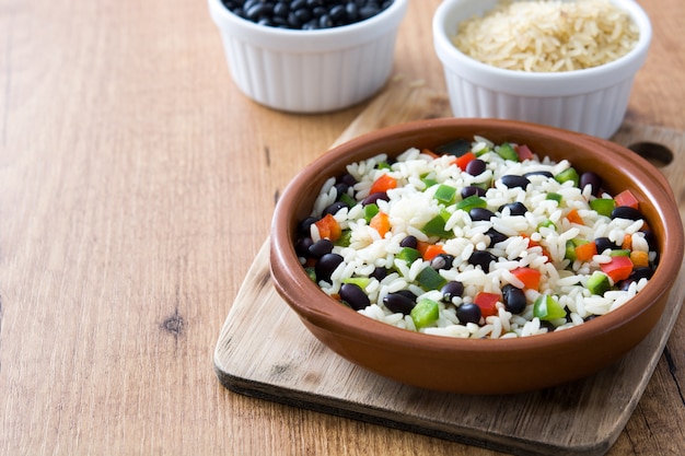 Traditional cuban rice, black beans and pepper on wooden table