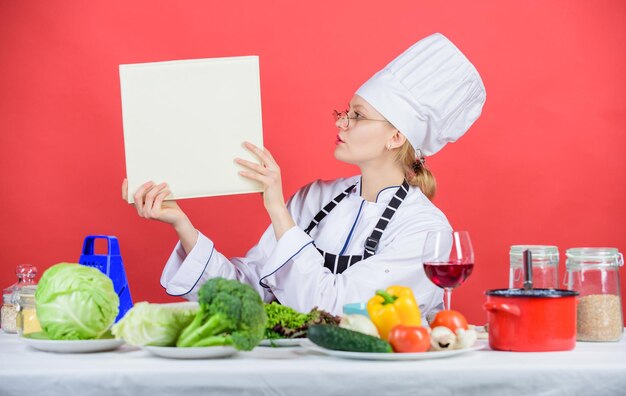 Traditional cuisine Culinary expert Woman chef cooking healthy food Girl read book top best culinary recipes Culinary school concept Female in hat and apron knows everything about culinary arts