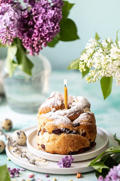 Traditional cupcake Easter cake kraffin with raisins and icing sugar on the table. Easter cakes, candles and a bouquet of lilac flowers.