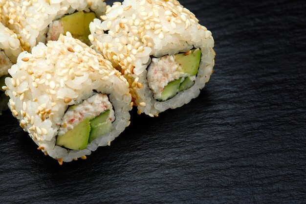 Traditional delicious fresh sushi roll set on a black\
background sushi roll with rice cream cheese avocado salmon sesame\
philadelphia sushi menu japanese kitchen restaurant