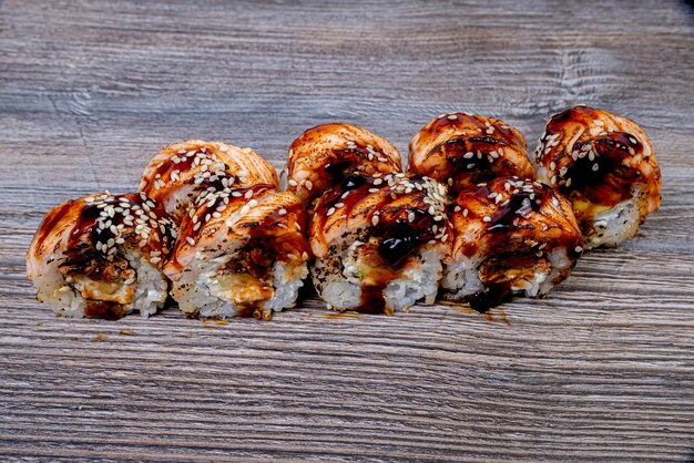 Традиционный вкусный свежий суши-ролл на черном фоне с отражением Суши-ролл с рисом, сливочным сыром, авокадо, лососем, кунжутом, Филадельфия, суши-меню, японская кухня