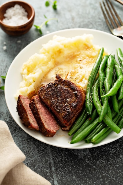 Traditional dinner meal with a bacon wrapped steak and potatoes