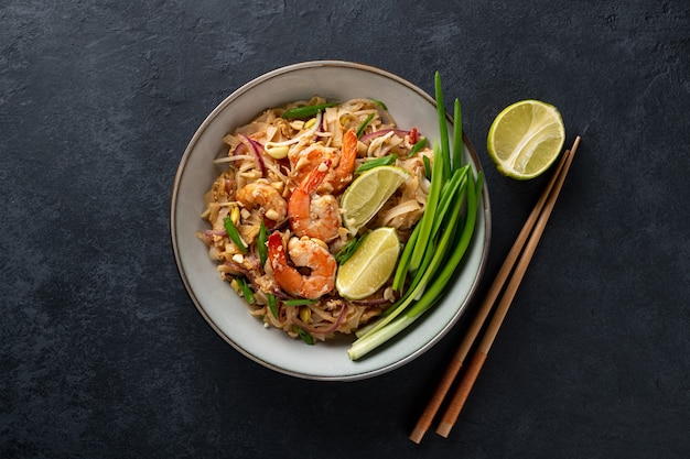 Traditional dish pad thai with shrimp on a dark stone background top view