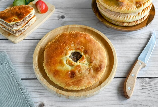 The traditional dish of the peoples of the Caucasus is Karachai khychins Ossetian pies with meat on a wooden board Light wooden background top view copy space