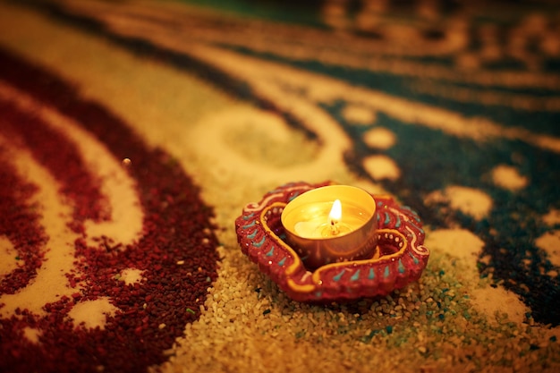 Foto lampada diya tradizionale accesa su rangoli colorati