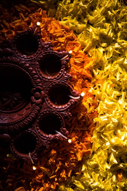 Traditional diya or oil lamp lit on colorful rangoli made up of flower petal, on the festival of lights called diwali or deepawali, selective focus