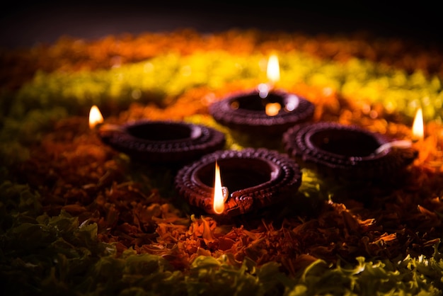 Traditional diya or oil lamp lit on colorful rangoli made up of flower petal, on the festival of lights called diwali or deepawali, selective focus