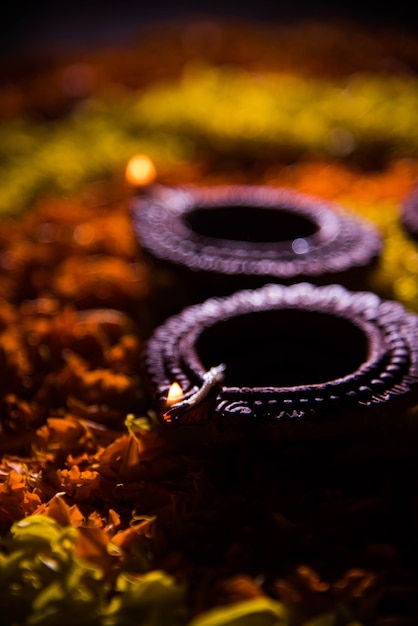 Traditional diya or oil lamp lit on colorful rangoli made up of flower petal, on the festival of lights called diwali or deepawali, selective focus